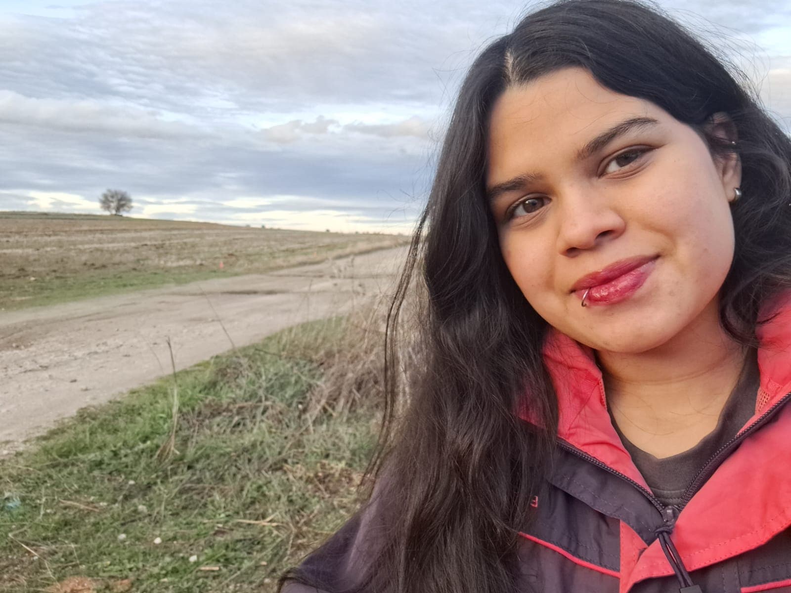 Alexandra smiling on a country path under a cloudy sky